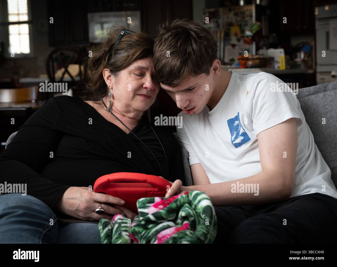 Ft. Mill, South Carolina, USA. März 2025. Beth Hodges, alleinerziehende Mutter, mit ihrem 19-jährigen Sohn Jack, der eine seltene Krampfanfallsstörung namens Dravet-Syndrom sowie Autismus der Stufe 3 hat. „Er hat die Bedürfnisse eines Kleinkindes in einem männlichen Körper“, erklärt sie. Wagenheber erfordert 24/7 Pflege. Beth plant, den Staat zu verlassen, sobald Jack mit 21 Jahren aus dem Bildungssystem des Staates gealtert ist. "Hier ist nichts für ihn", sagte sie. (Kreditbild: © Robin Rayne/ZUMA Press Wire) NUR REDAKTIONELLE VERWENDUNG! Nicht für kommerzielle ZWECKE! Stockfoto