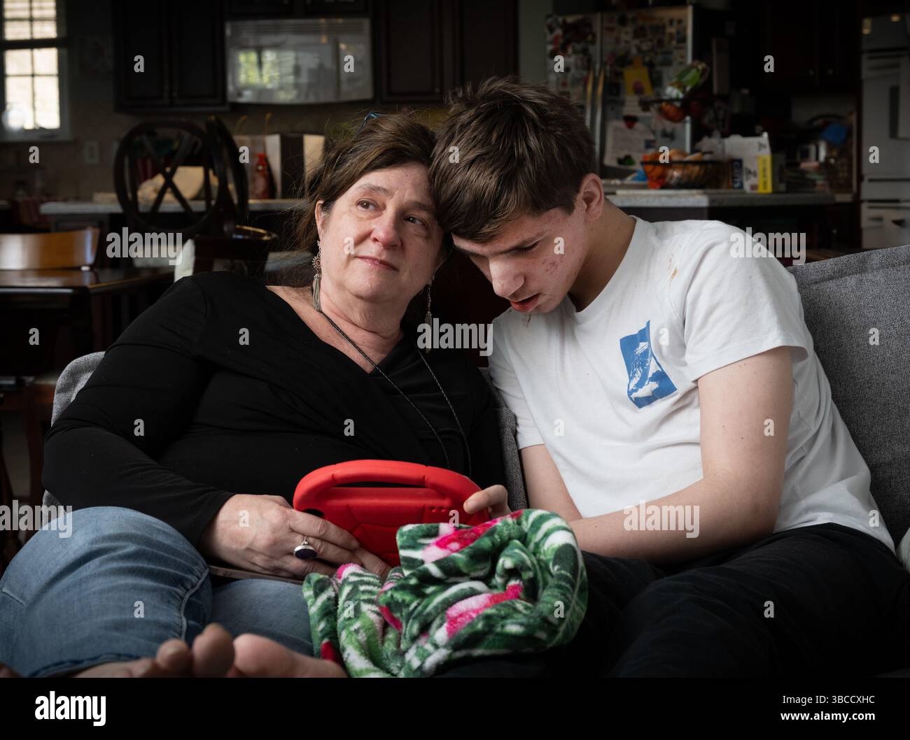 Ft. Mill, South Carolina, USA. März 2025. Beth Hodges, alleinerziehende Mutter, mit ihrem 19-jährigen Sohn Jack, der eine seltene Krampfanfallsstörung namens Dravet-Syndrom sowie Autismus der Stufe 3 hat. „Er hat die Bedürfnisse eines Kleinkindes in einem männlichen Körper“, erklärt sie. Wagenheber erfordert 24/7 Pflege. Beth plant, den Staat zu verlassen, sobald Jack mit 21 Jahren aus dem Bildungssystem des Staates gealtert ist. "Hier ist nichts für ihn", sagte sie. (Kreditbild: © Robin Rayne/ZUMA Press Wire) NUR REDAKTIONELLE VERWENDUNG! Nicht für kommerzielle ZWECKE! Stockfoto
