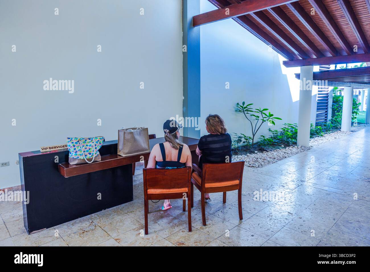 Zwei Frauen sitzen am VIP-Serviceschalter im Hotelflur und haben Reisegepäck auf der Theke. Punta Cana. Dominikanische Republik. 05.19.2025. Stockfoto