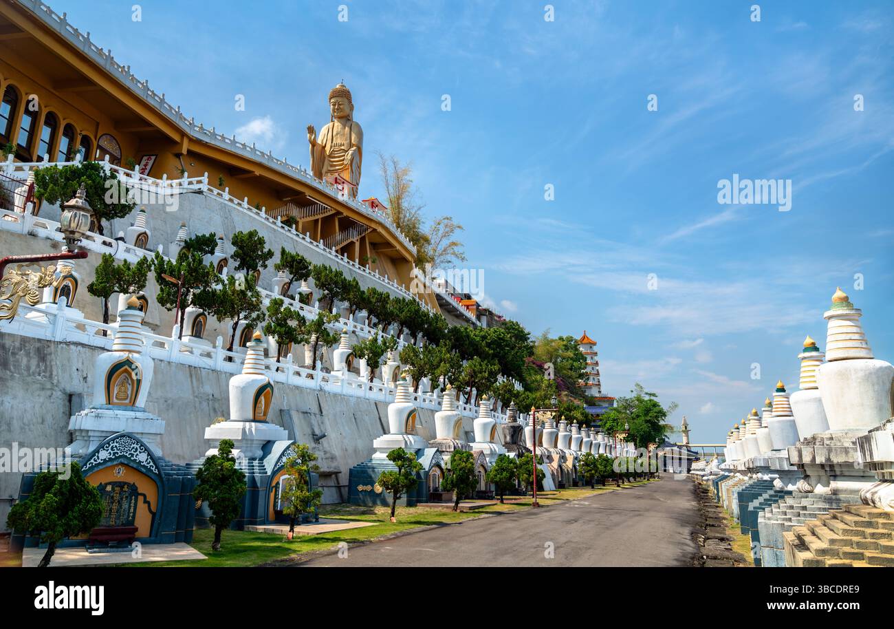 Majestätischer Blick auf das Kloster Fo Guang Shan in Kaohsiung, Taiwan, mit der majestätischen goldenen Buddha-Statue mit Blick auf einen terrassenförmig angelegten Hügel, der mit Stupas, Bonsai-Bäumen und traditioneller chinesischer Architektur geschmückt ist. Der klare Himmel und die symmetrische Ausrichtung der Strukturen schaffen eine ruhige und monumentale Atmosphäre an diesem berühmten buddhistischen Wallfahrtsort Stockfoto