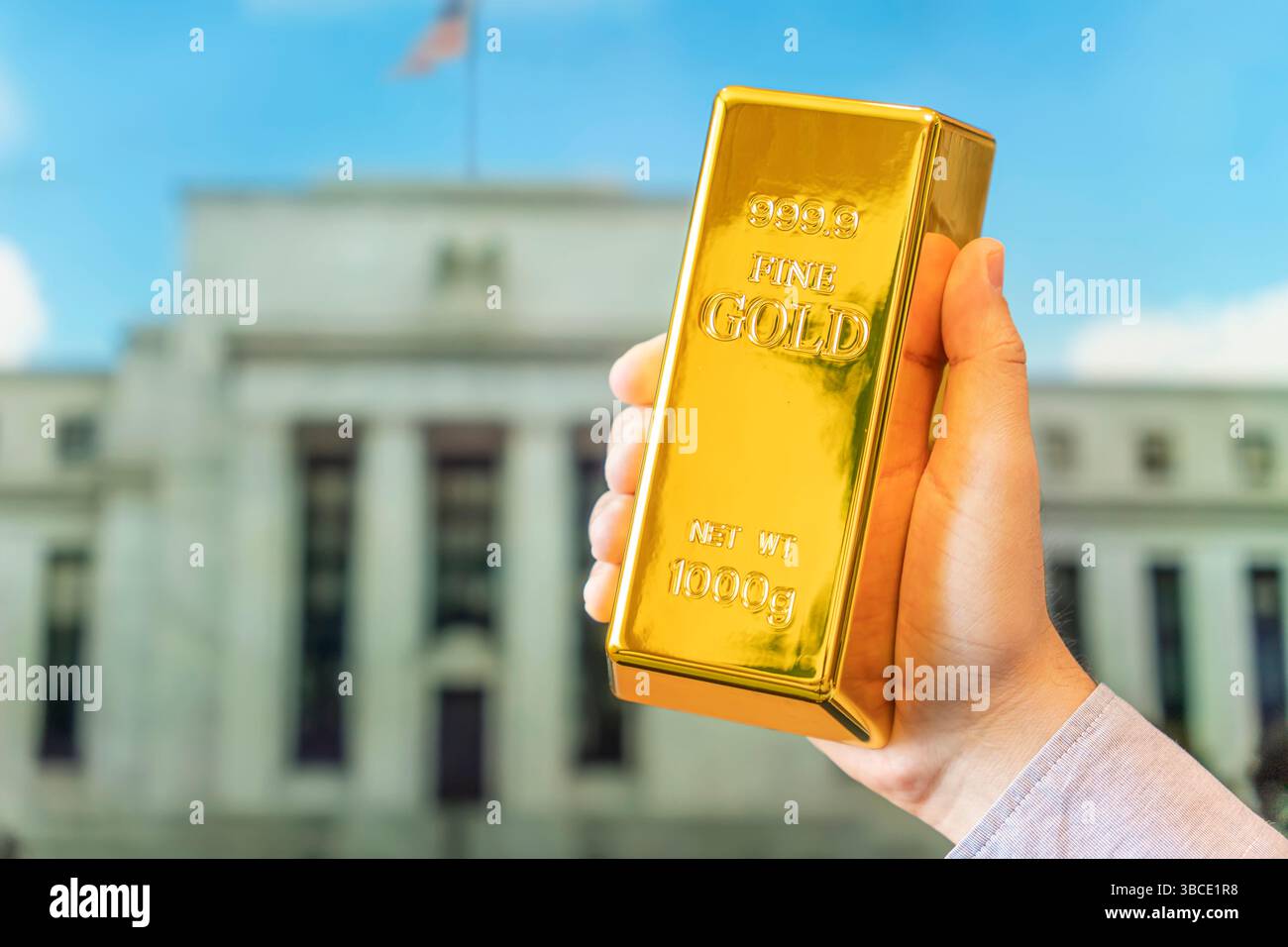 Ein Goldbarren in der Hand eines Mannes vor dem Hintergrund des Notenbanksystems der US Federal Reserve. Stockfoto