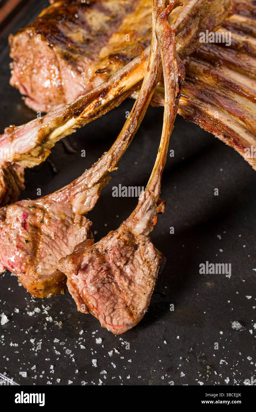 Lammregale gegrillt mit Kräutern und Soße auf einem Steinbrett Stockfoto
