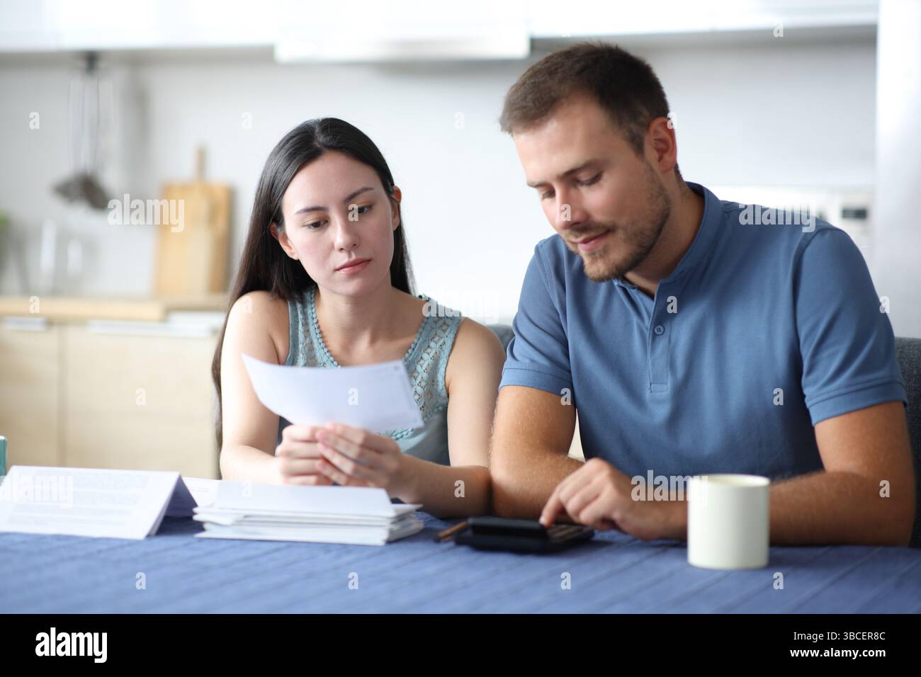 Interrassisches Paar berechnet die Kosten, die Rechnung in der Küche zu Hause lesen Stockfoto