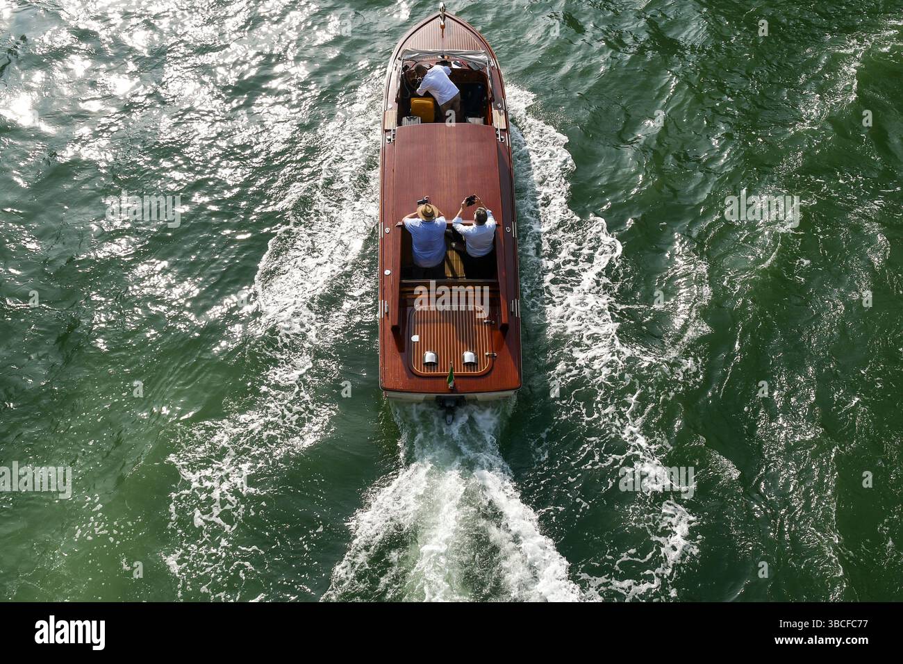 Aus der Vogelperspektive eines luxuriösen Wassertaxis auf dem Canal Grande, mit drei Männern an Bord im Sommer, Venedig, Venetien, Italien Stockfoto