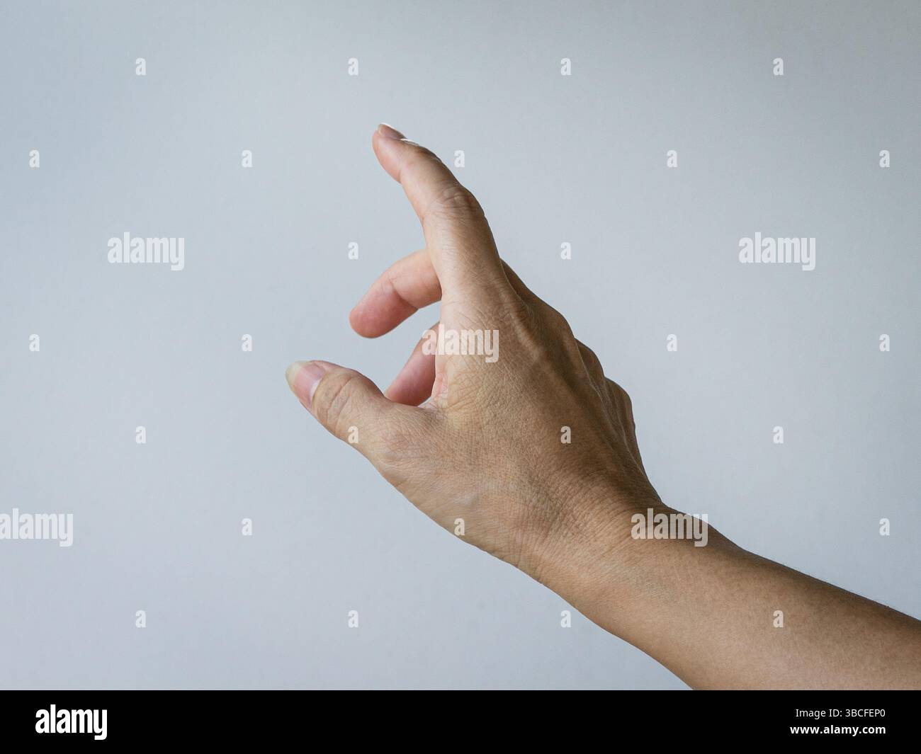 Die weibliche Hand bildet eine zeigende Geste. Vor weißem Hintergrund. Stockfoto