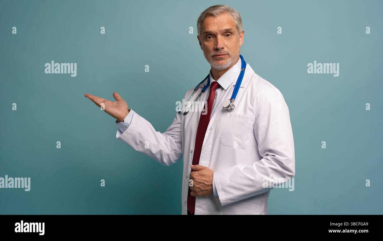 Gutaussehender Doktor Mann trägt medizinische Uniform über isoliertem Hintergrund lächelnd fröhlich präsentieren und mit Handfläche zeigen Stockfoto