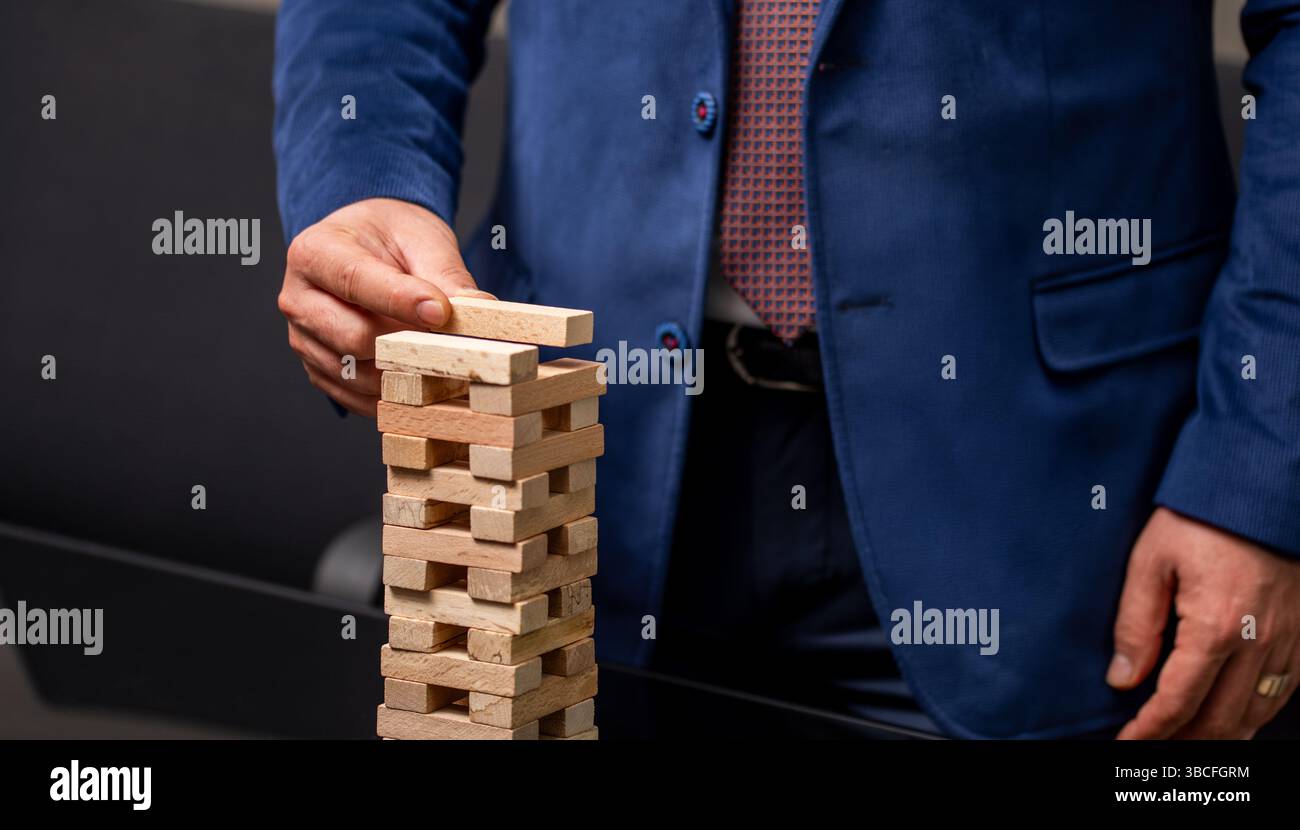 Geschäftsmann platziert Holzblock auf Turm. Wachstum und Strategiekonzept. Hochwertige Fotos Stockfoto