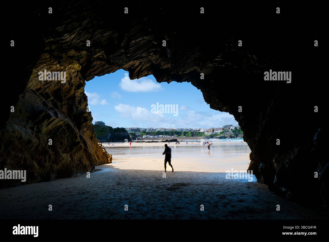 Die Figur eines männlichen Urlaubers, der eine tiefe Höhle am sonnigen GT Great Western Beach in Newquay in Cornwall in Großbritannien betritt. Stockfoto