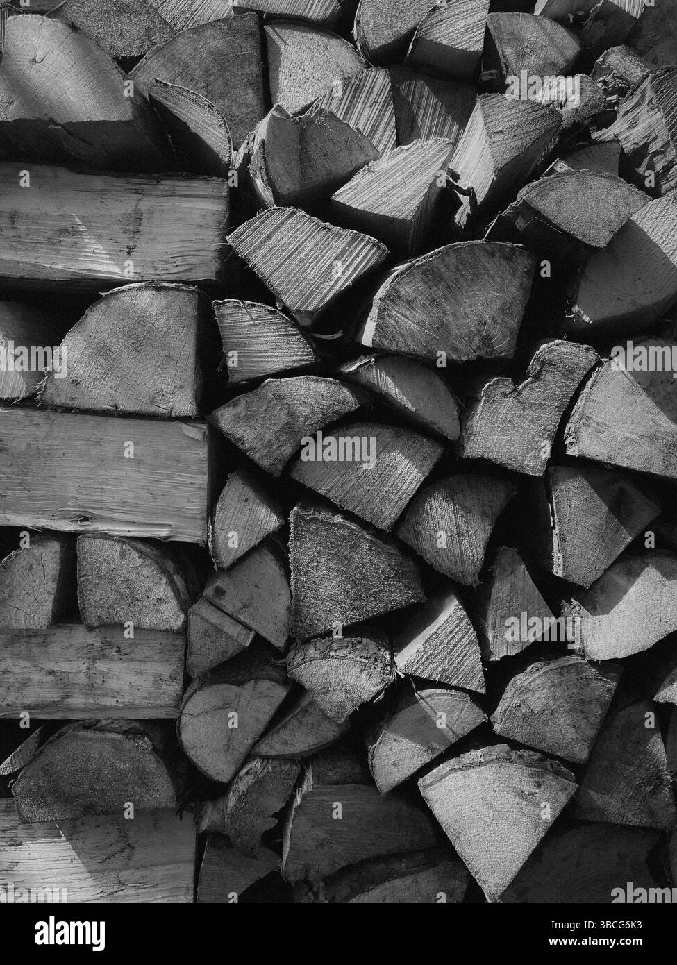 Schwarz-weiße Nahaufnahme von Stapeln aus Brennholz mit rauen Texturen und natürlichen Holzmaserungen. Stockfoto