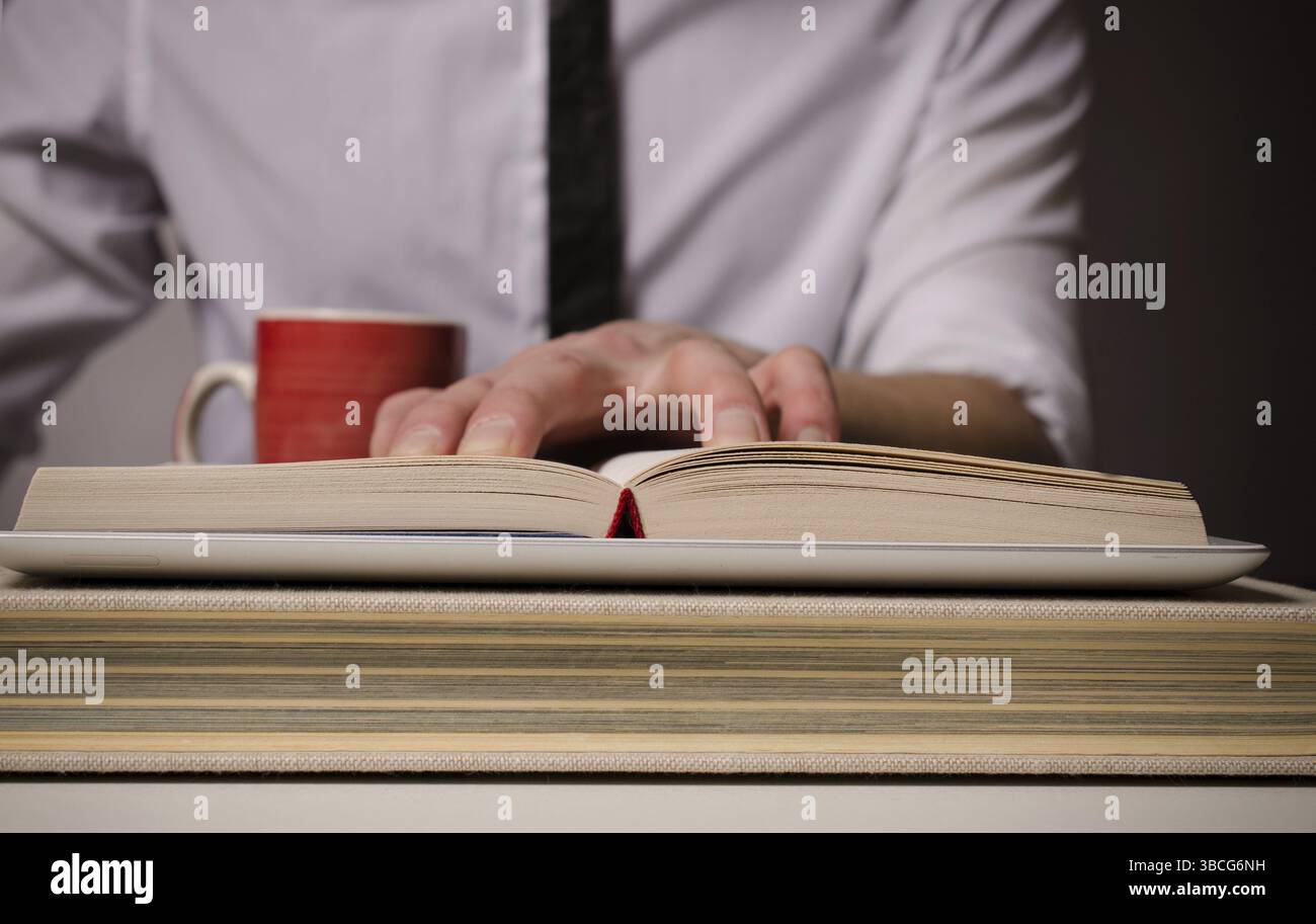 Geschäftsmann, einem großen Buch auf einem Tabletcomputer Stockfoto