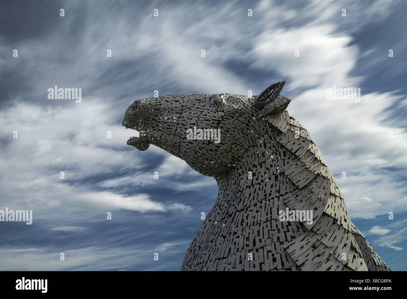 Falkirk, Vereinigtes Königreich - 20. Juni 2022: Eine der Kelpies-Pferdekopfskulpturen mit einem ausdrucksstarken, langbelichteten Himmel dahinter Stockfoto