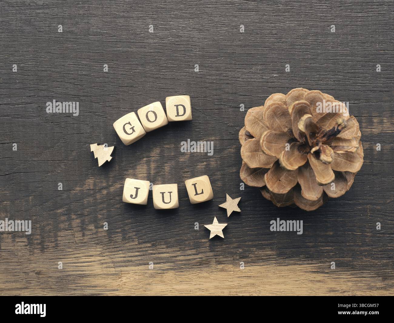 Kiefernkegel und Holzdices mit den Worten God Jul, Scandinavian Merry Christmas Stockfoto