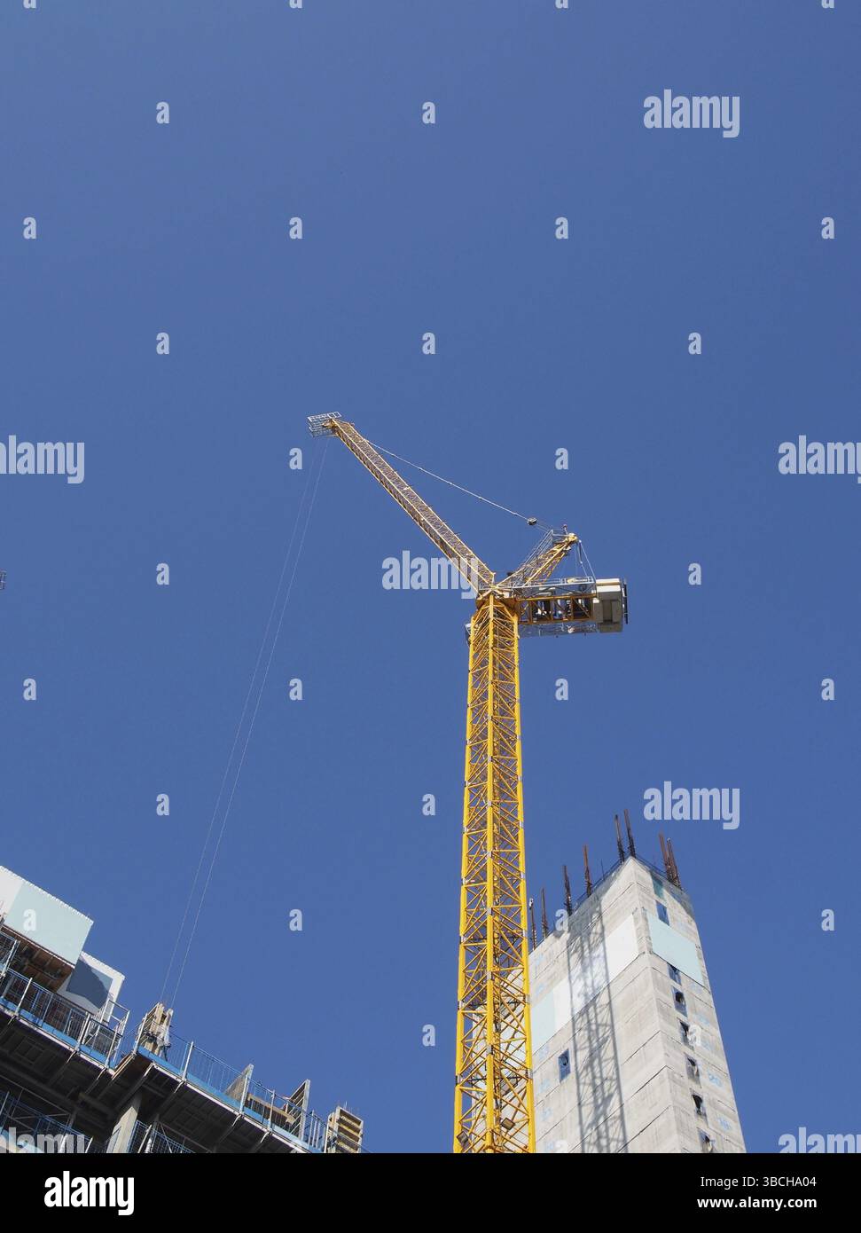 Blick auf einen hohen Turmkran, der auf großen Baustellen vor blauem Himmel arbeitet Stockfoto