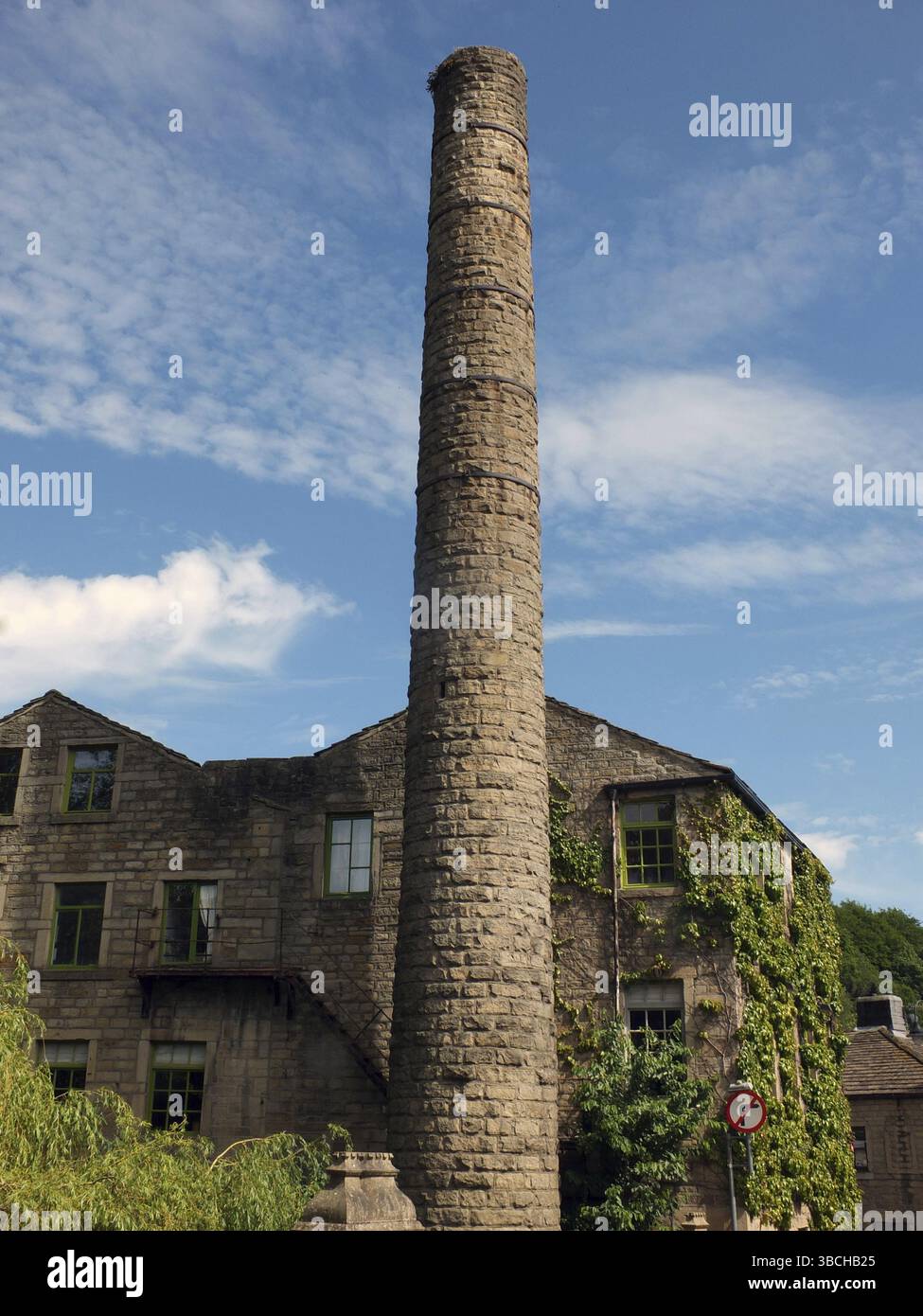 Ein altes Mühlengebäude und hoher Kamin mit blauem, bewölktem Himmel in hebden Bridge West yorkshire Stockfoto