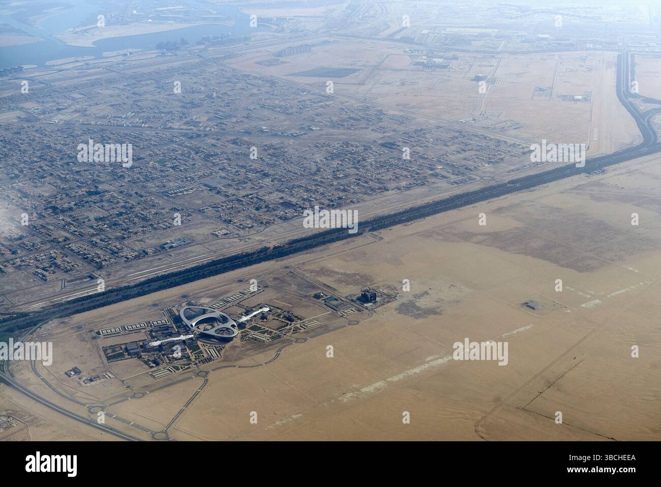 Luftaufnahme von Stadt- und Wüstenlandschaften mit einer deutlichen Grenze zwischen entwickeltem und trockenem Land. Abu Dhabi, VAE Stockfoto