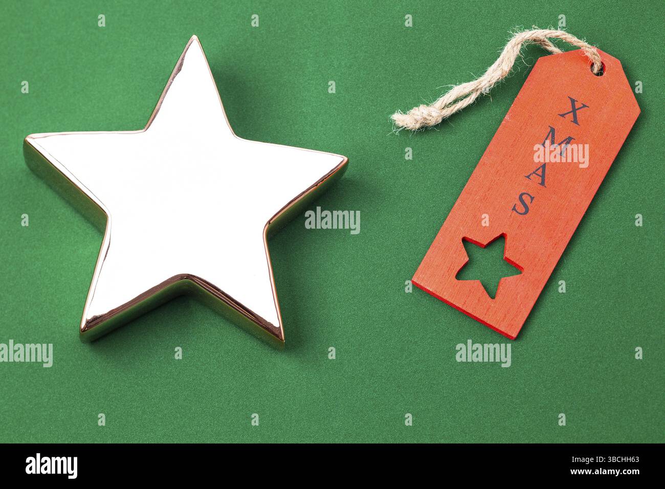 Das Foto zeigt einen goldenen Stern mit einem roten Weihnachtsetikett auf grünem Hintergrund Stockfoto