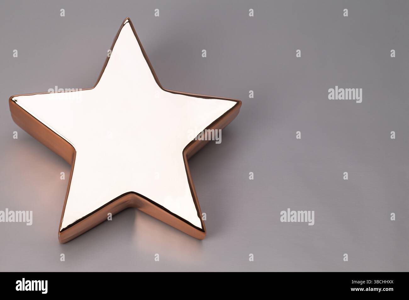 Das Foto zeigt einen goldenen Stern mit einem roten Weihnachtsetikett auf grünem Hintergrund Stockfoto