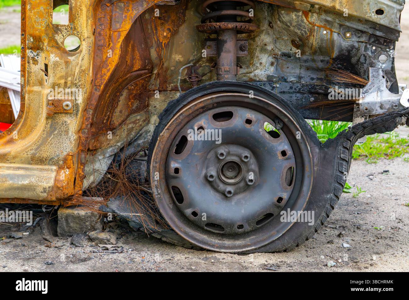 Rostiger Radlauf und verbrannter Innenraum eines alten Autos mit beschädigtem Rad. Sichtbare Anzeichen von Feuer, Korrosion und Materialverschleiß. Stockfoto