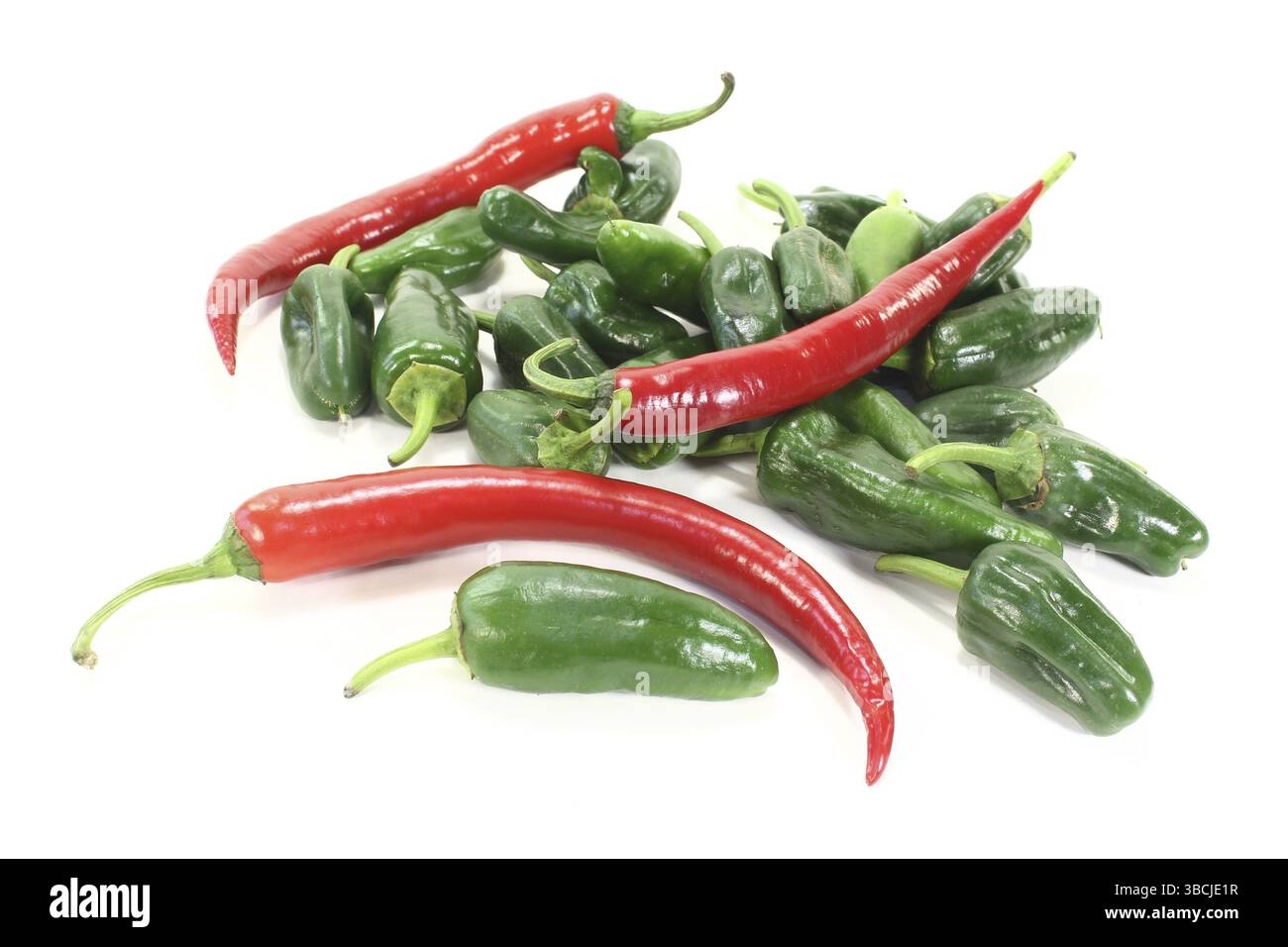 Grüne Pimientos und rote Chilis auf einem Stapel vor hellem Hintergrund Stockfoto