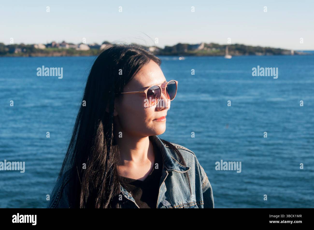 Eine chinesin mit Sonne im Gesicht im Fort Wetherill State Park in Jamestown, Rhode Island. Stockfoto