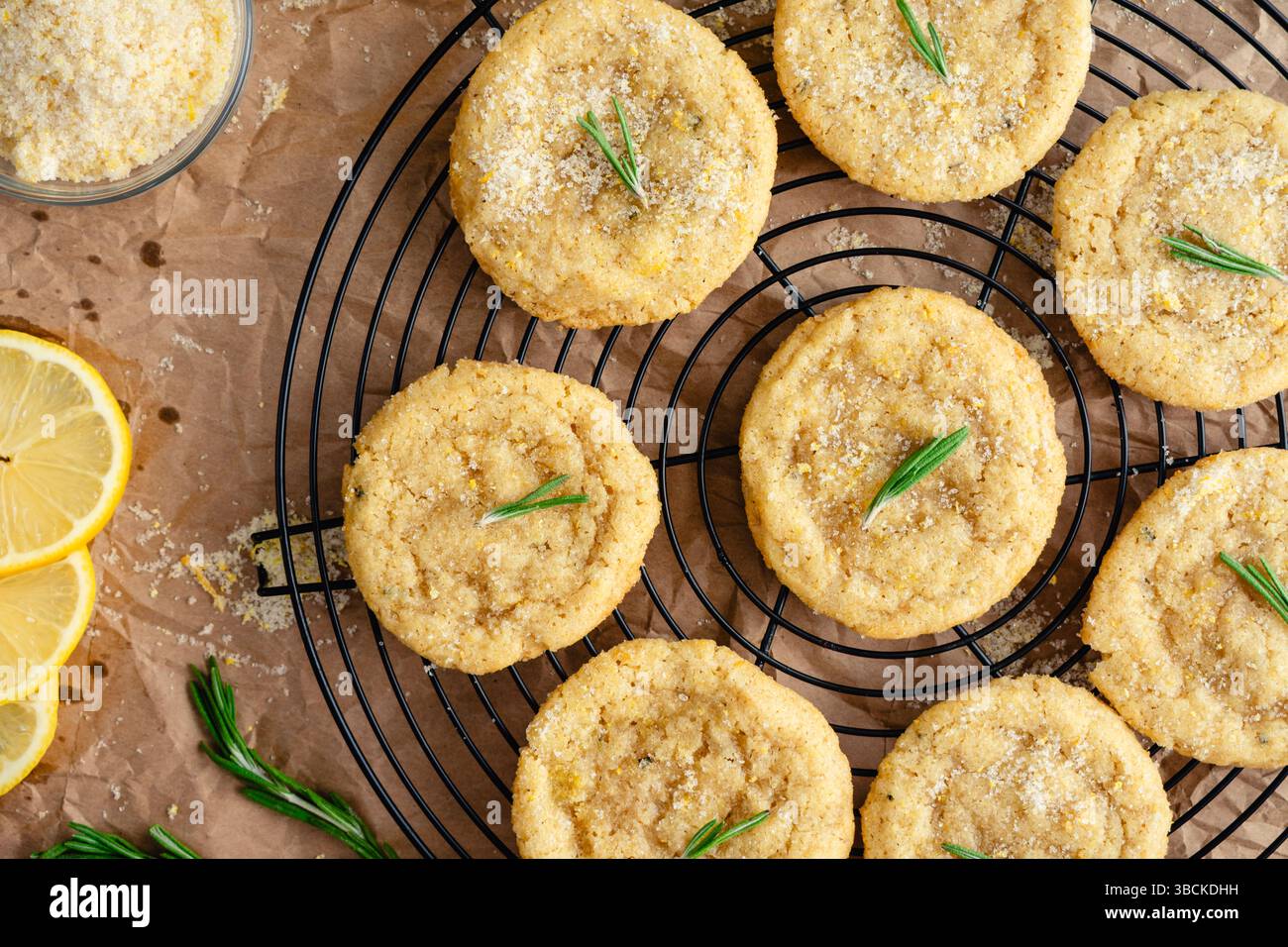 Rosmarin-Lemon Sugar Plätzchen auf Round Wire Cooling Rack: Ober-Nahaufnahme von frisch gebackenen selbstgemachten Zuckerkeksen, die auf einem Drahtrad abkühlen Stockfoto