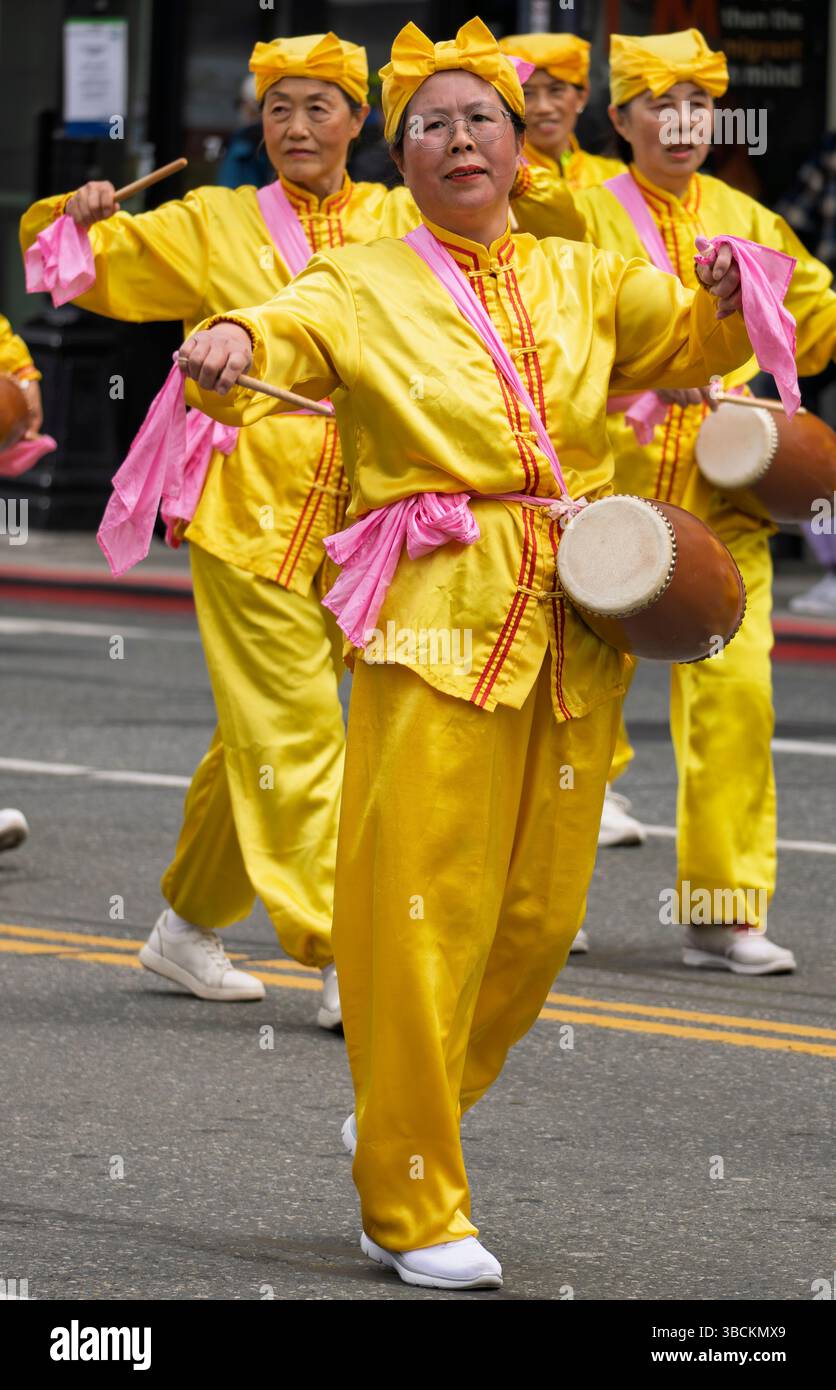 Trommler in gelben Kostümen bei der Victoria Day Parade am 19. Mai 2025 in Victoria, British Columbia, Kanada. Stockfoto