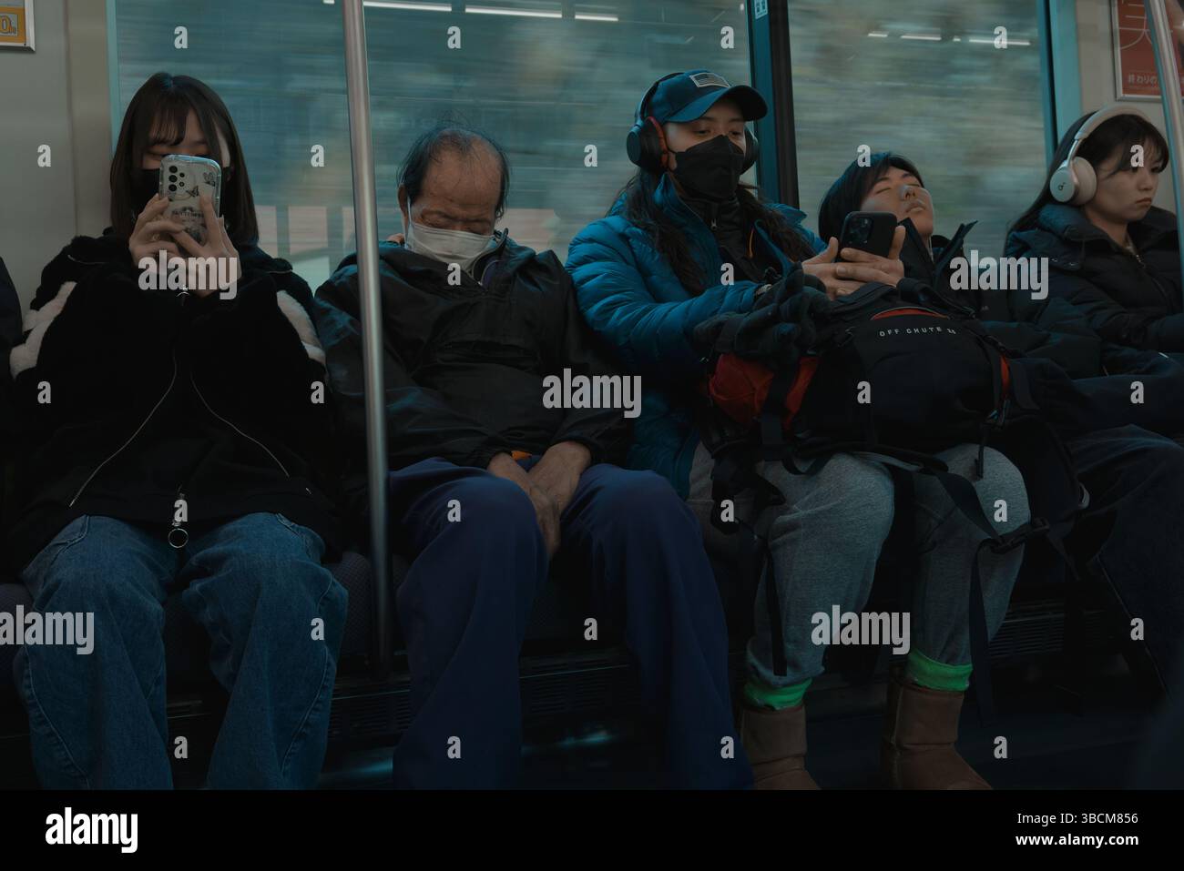 Passagiere in ihrer eigenen Welt – einige schlafen, andere scrollen – auf einer ruhigen U-Bahn-Fahrt Stockfoto