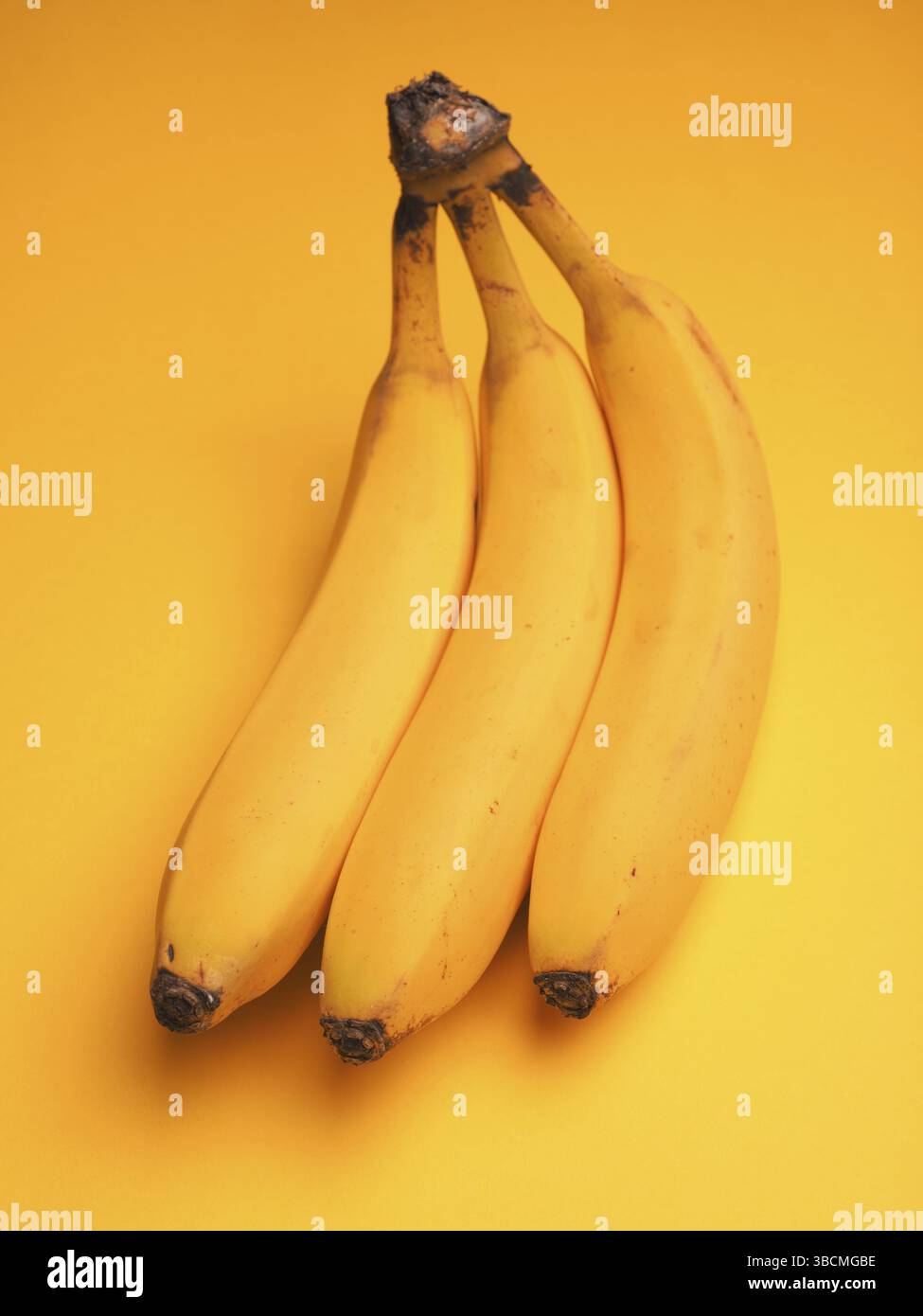 Drei frische Bananen auf gelbem Hintergrund Stockfoto