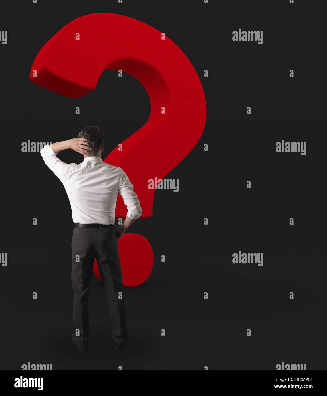 Business-Mann mit einem großen roten Fragezeichen auf einem dunklen Hintergrund Stockfoto