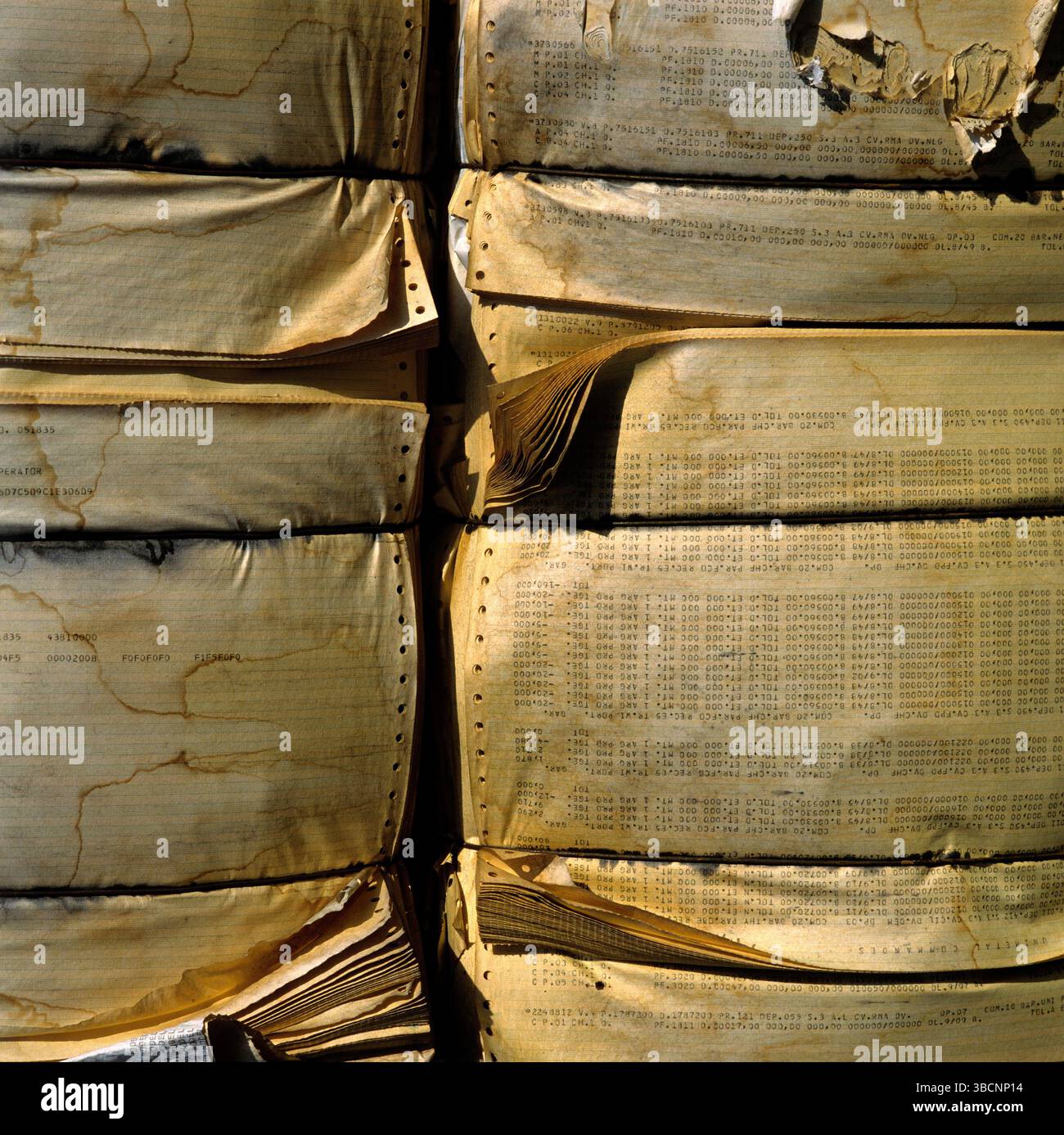 Ein großer Stapel komprimierter Papierprodukte ist in einem Recyclingbereich angeordnet. Das Papier weist auf Verschleiß hin und weist auf seine vorherige Verwendung hin. Stockfoto