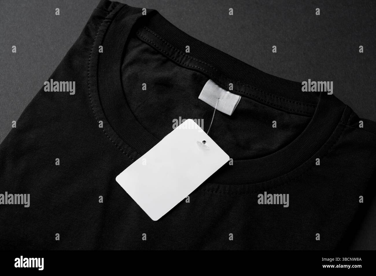 Nahaufnahme des schwarzen T-Shirt-Kragens mit leerem weißem Etikett Stockfoto