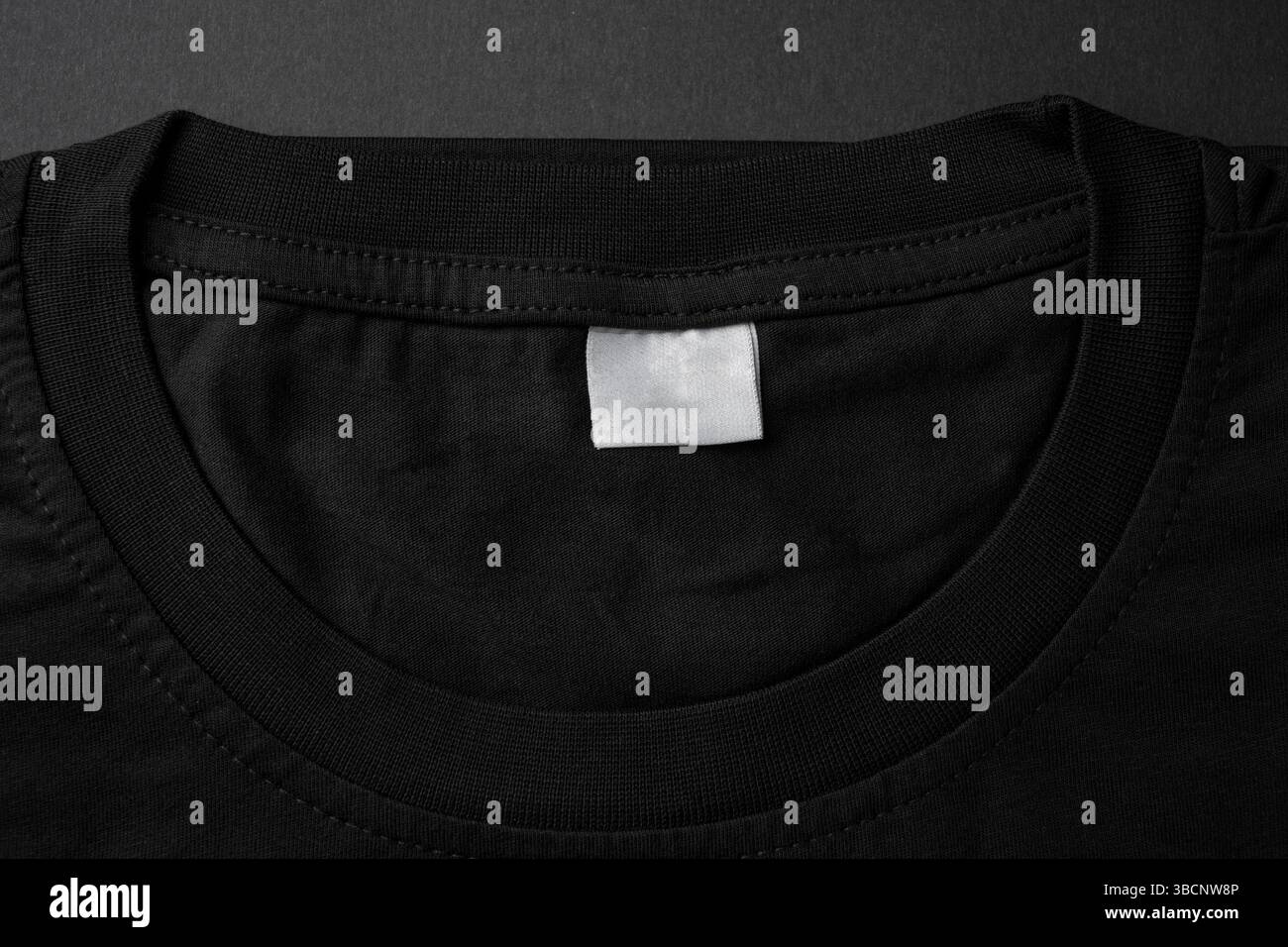 Nahaufnahme des schwarzen T-Shirt-Kragens mit leerem weißem Etikett Stockfoto