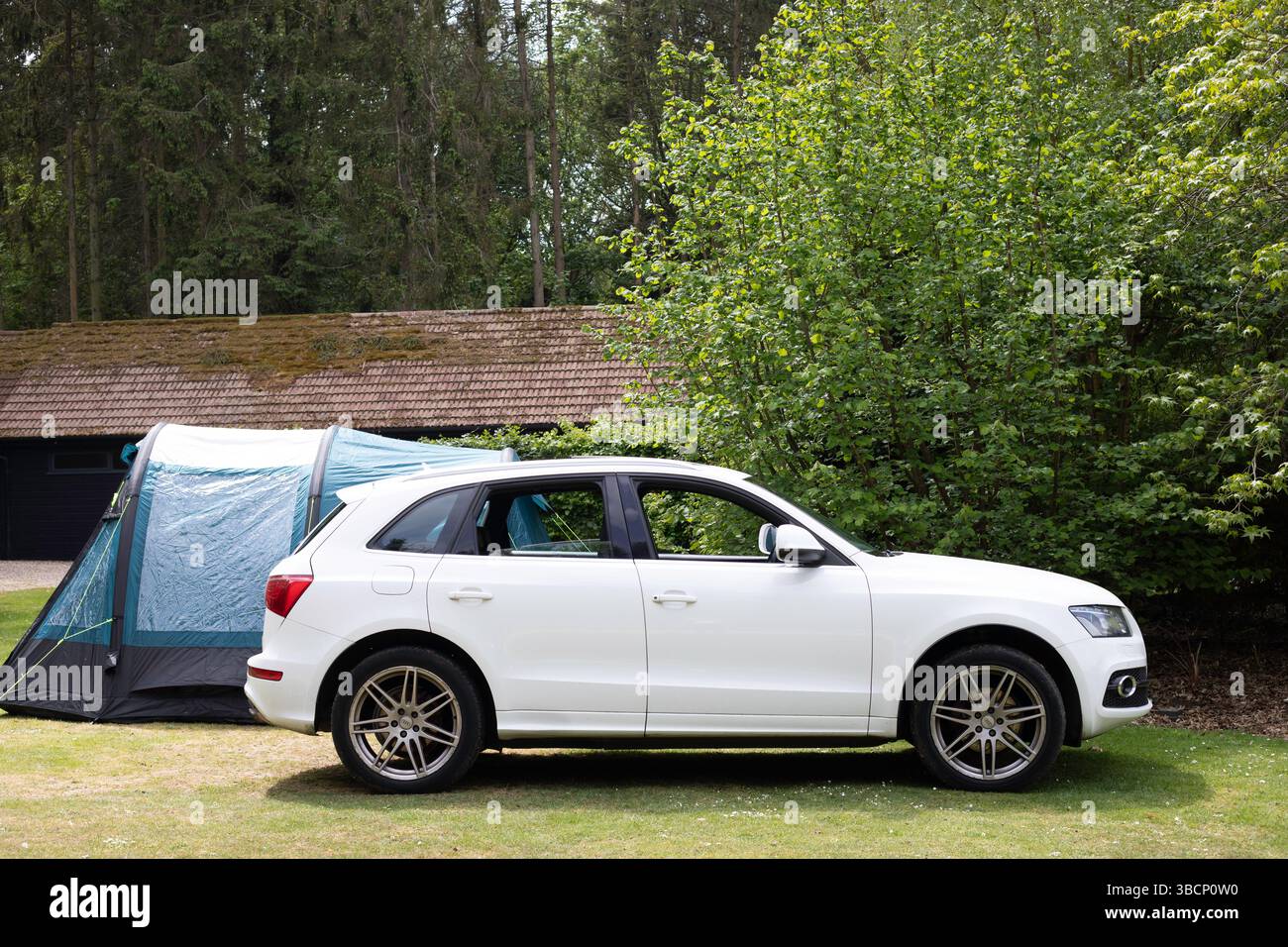 Ein weißes Auto und ein Zelt auf einem Campingplatz im Wald Stockfoto