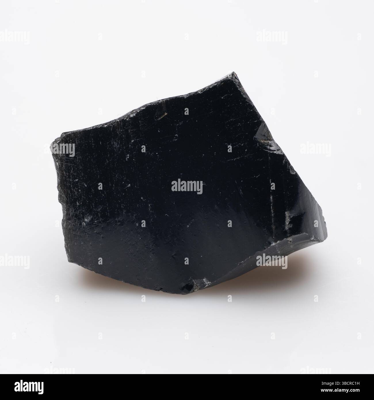 Volcanic Glass Fragment: Ein rohes Obsidianstück, das eine dunkle, glänzende Oberfläche und einen winkligen Bruch aufweist - eine natürliche Felsformation für die Geologie-Studie. Stockfoto