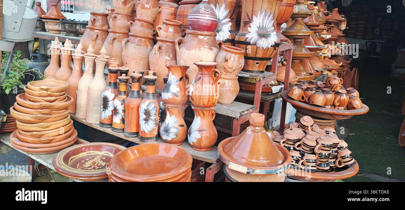 Abwechslungsreiche bunte marokkanische Terrakotta-Töpferwaren einschließlich handbemalter: Tagines, Teller, Tangia-Gläser, Töpfe oder Behälter, traditionelle Tassen, und Wassergläser Stockfoto