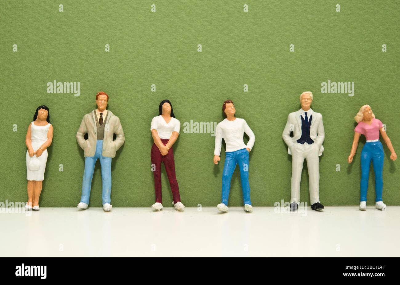 Miniaturfiguren von Menschen, die an einer Wand ausgerichtet sind Stockfoto