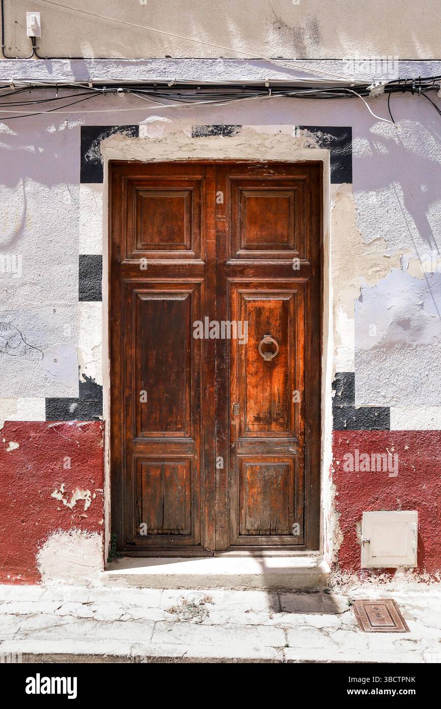 Alte Holztür mit abgebrochener Fassade in der Altstadt von Denia, Spanien Stockfoto