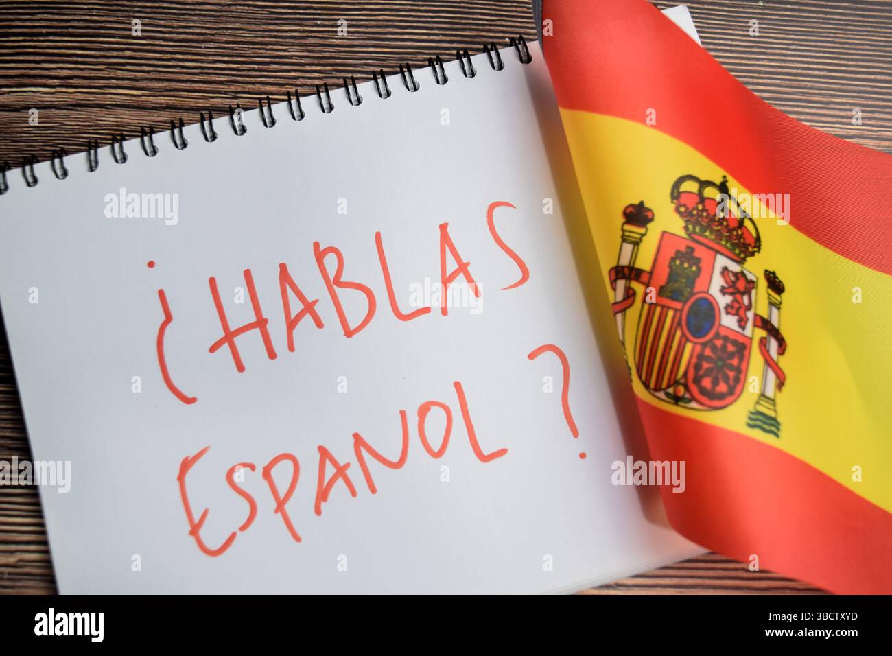 Konzept der mit Frage hablas espanol schreiben auf Buch und Flagge spaniens isoliert auf Holztisch. Stockfoto