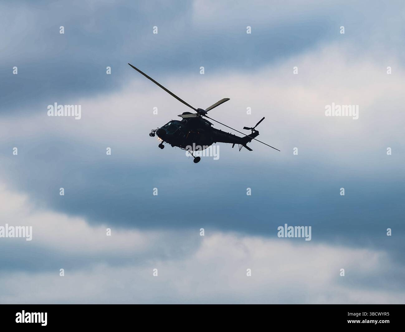 Seitenansicht eines Militärhubschraubers im Flug gegen einen türkisfarbenen Himmel, die Details des Flugzeugprofils erfasst und eine dynamische Luftfahrtszene erzeugt. Sammlung von Fotografien Stockfoto