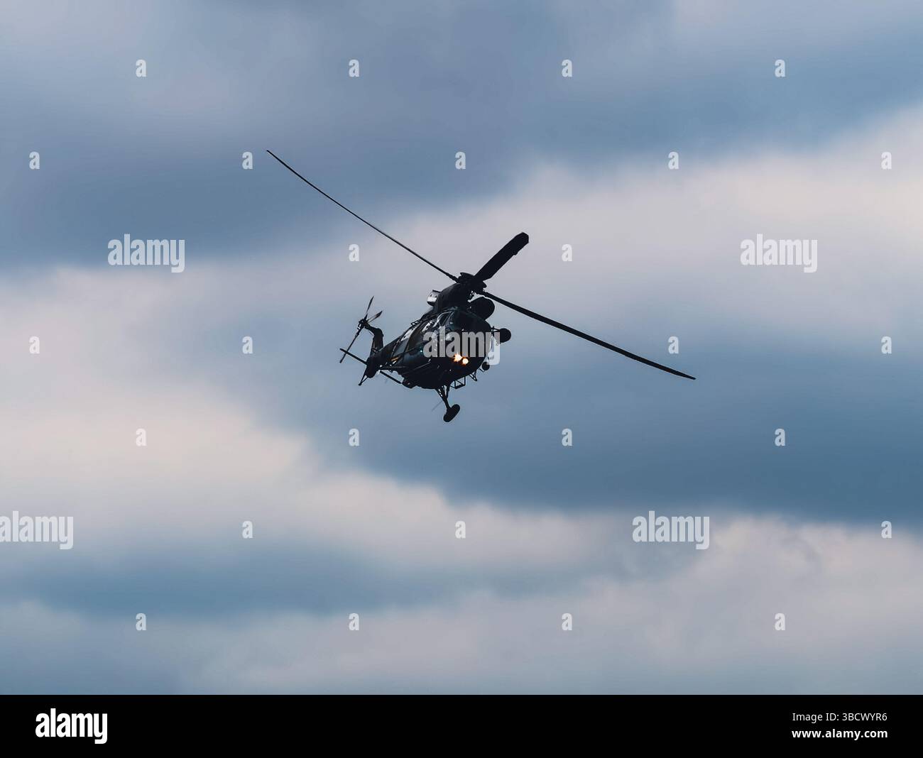 Seitenansicht eines Militärhubschraubers im Flug gegen einen türkisfarbenen Himmel, die Details des Flugzeugprofils erfasst und eine dynamische Luftfahrtszene erzeugt. Stock-Foto Stockfoto