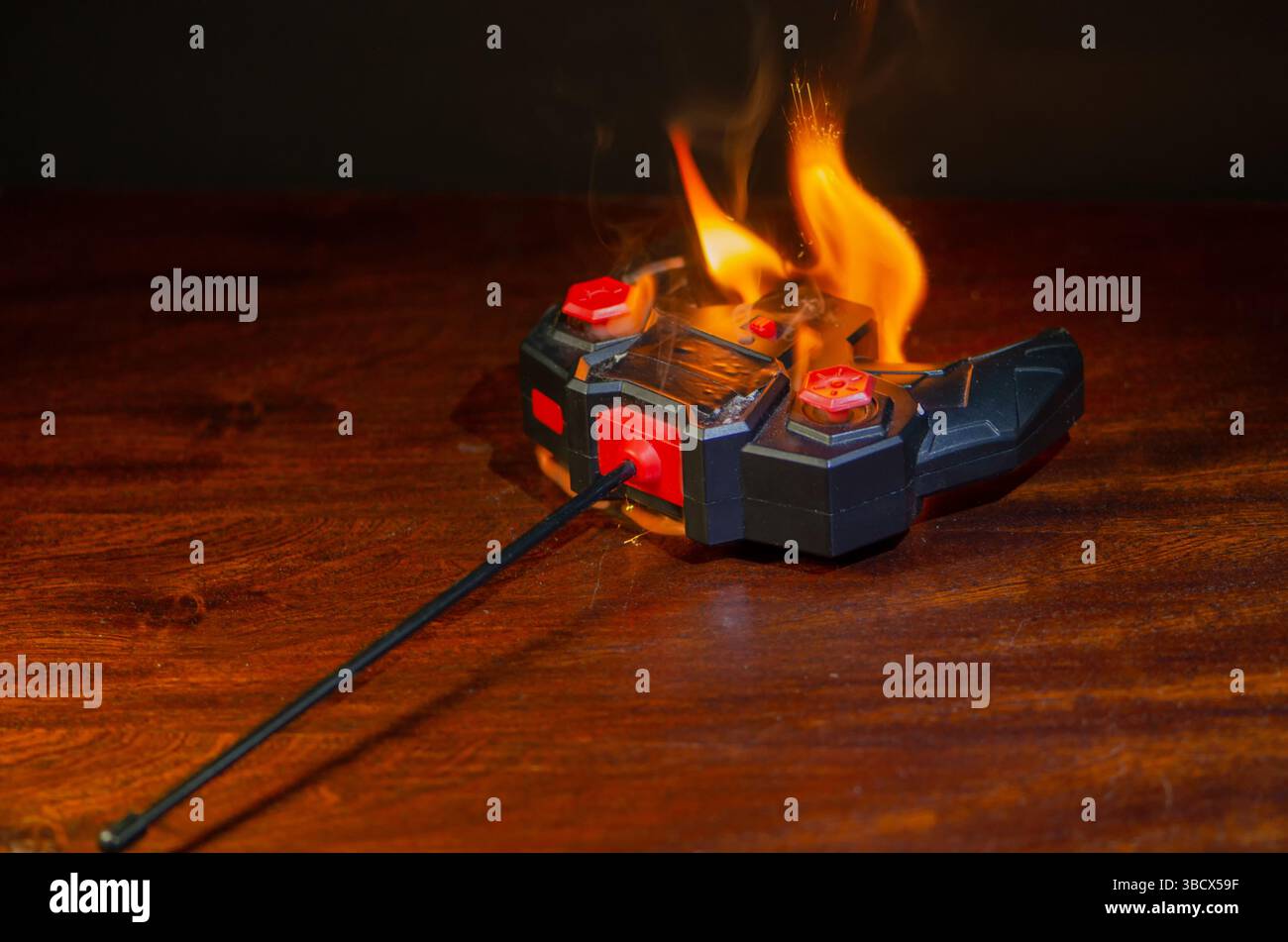 Gefahr der Spielzeugelektronik: Brennende Fernbedienung. Die Kunststofffernbedienung eines Kinderwagens ist in Flammen verwickelt Stockfoto