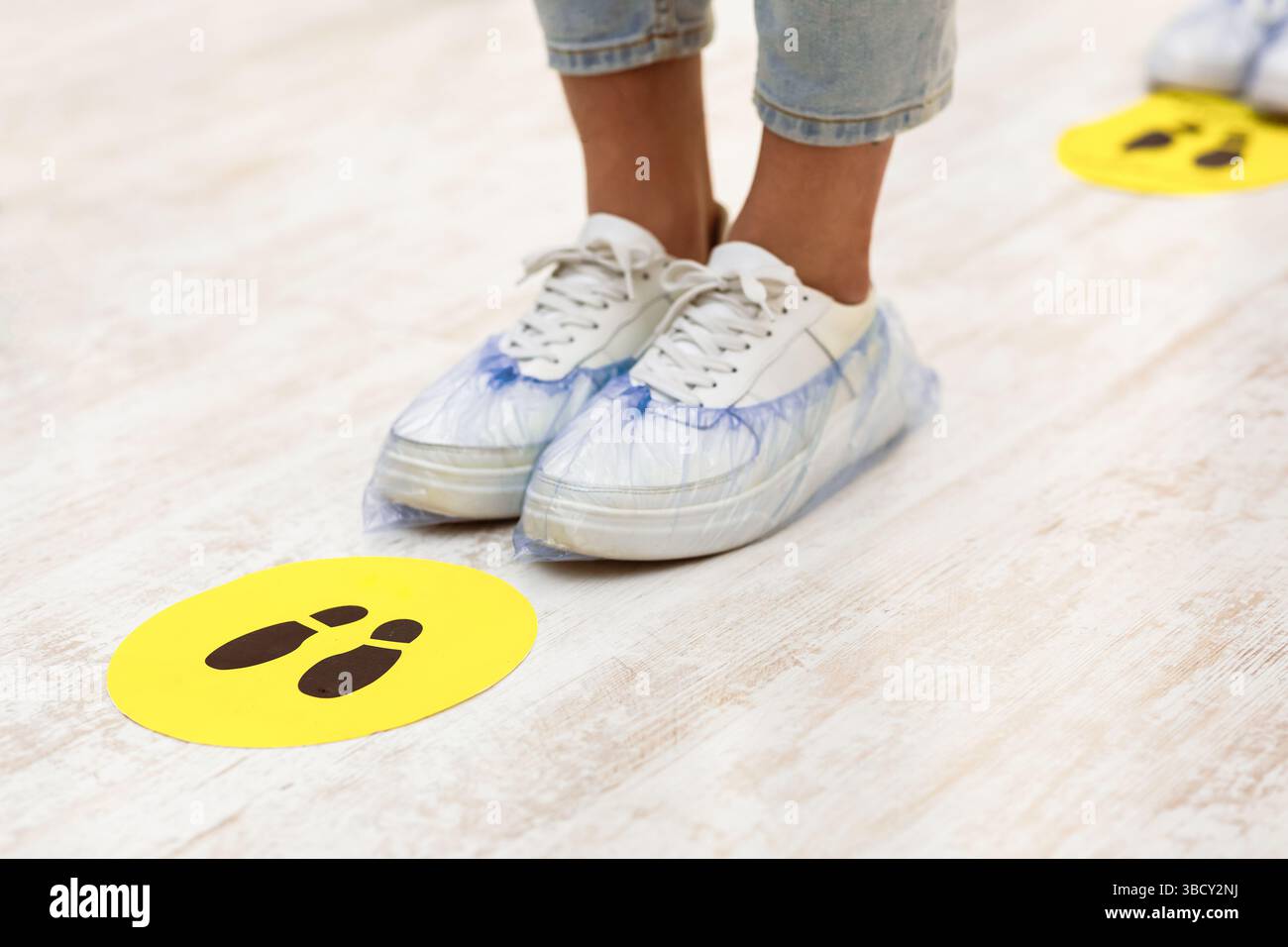 Mädchen Füße stehen in der Nähe von Social Distanzing Warnschild Innen Stockfoto