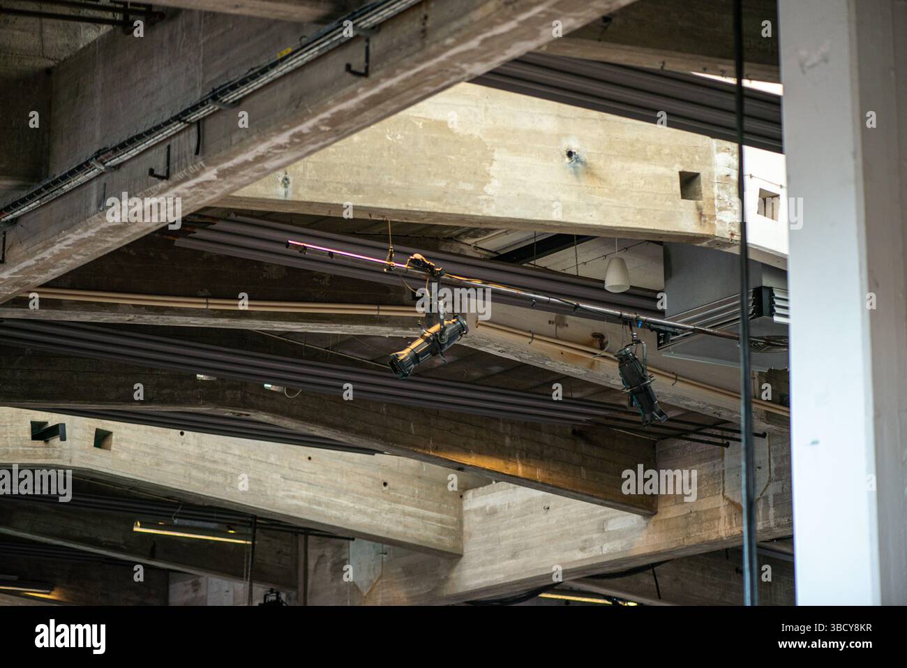 Eine detaillierte Ansicht der Verkabelung und Anschlüsse eines elektronischen Systems, die direkt an einer rohen Betondecke in einer modernen architektonischen Umgebung installiert sind. Stockfoto
