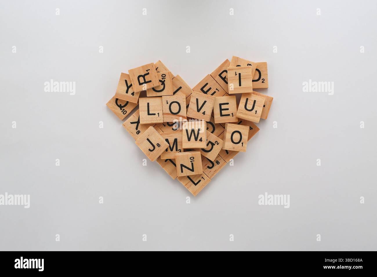 Scrabble-Fliesen in Herzform mit dem Wort „LIEBE“ als Mittelpunkt. Stockfoto