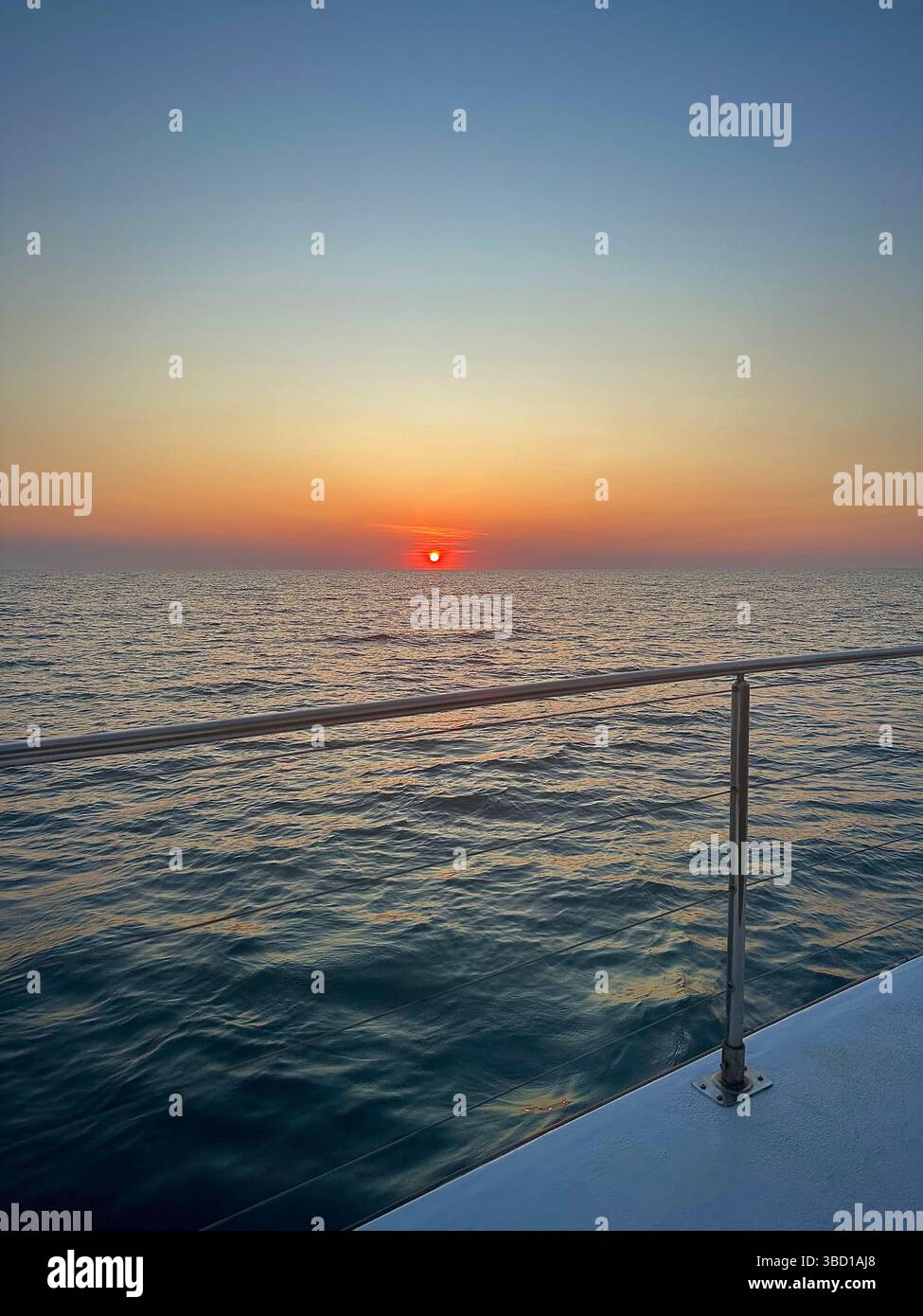 Blick auf den Sonnenuntergang über das ruhige Meer von einem Bootsdeck aus - perfekt für Reisen, Luxus-Lifestyle, Entspannung und nautische Themen. - Smartphone-aufgenommenes Stockfoto