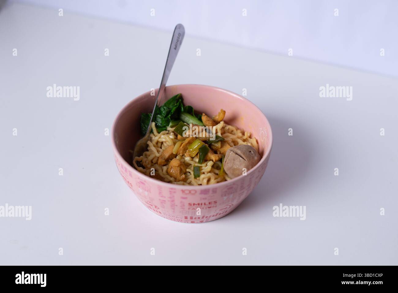 Eine Schüssel verführerischer Hühnchennudelsuppe mit Fleischbällchen und grünem Gemüse bietet eine angenehme hausgemachte Mahlzeit Stockfoto
