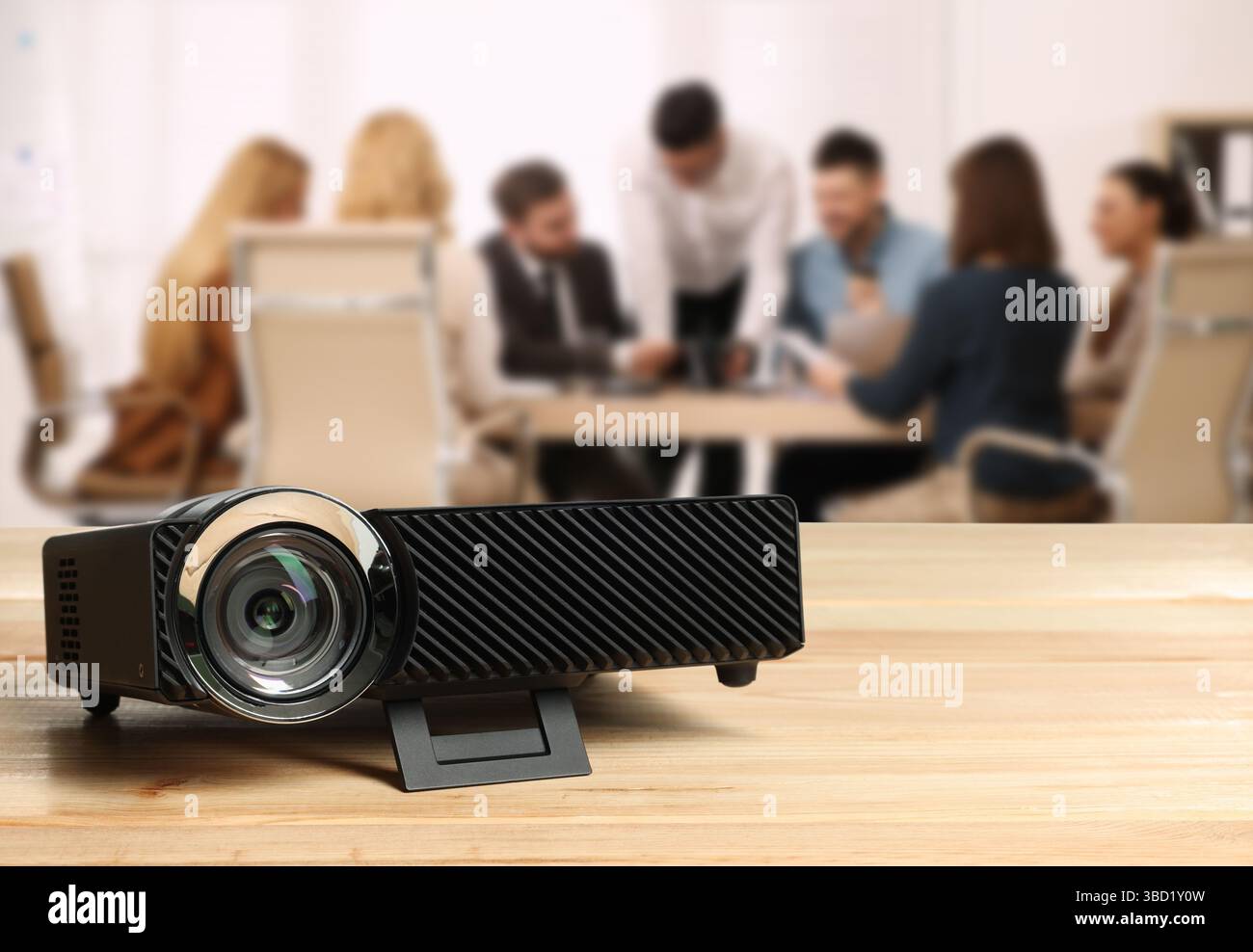 Moderner Videoprojektor auf Holztisch und Personen, die im Konferenzraum arbeiten, selektiver Fokus Stockfoto