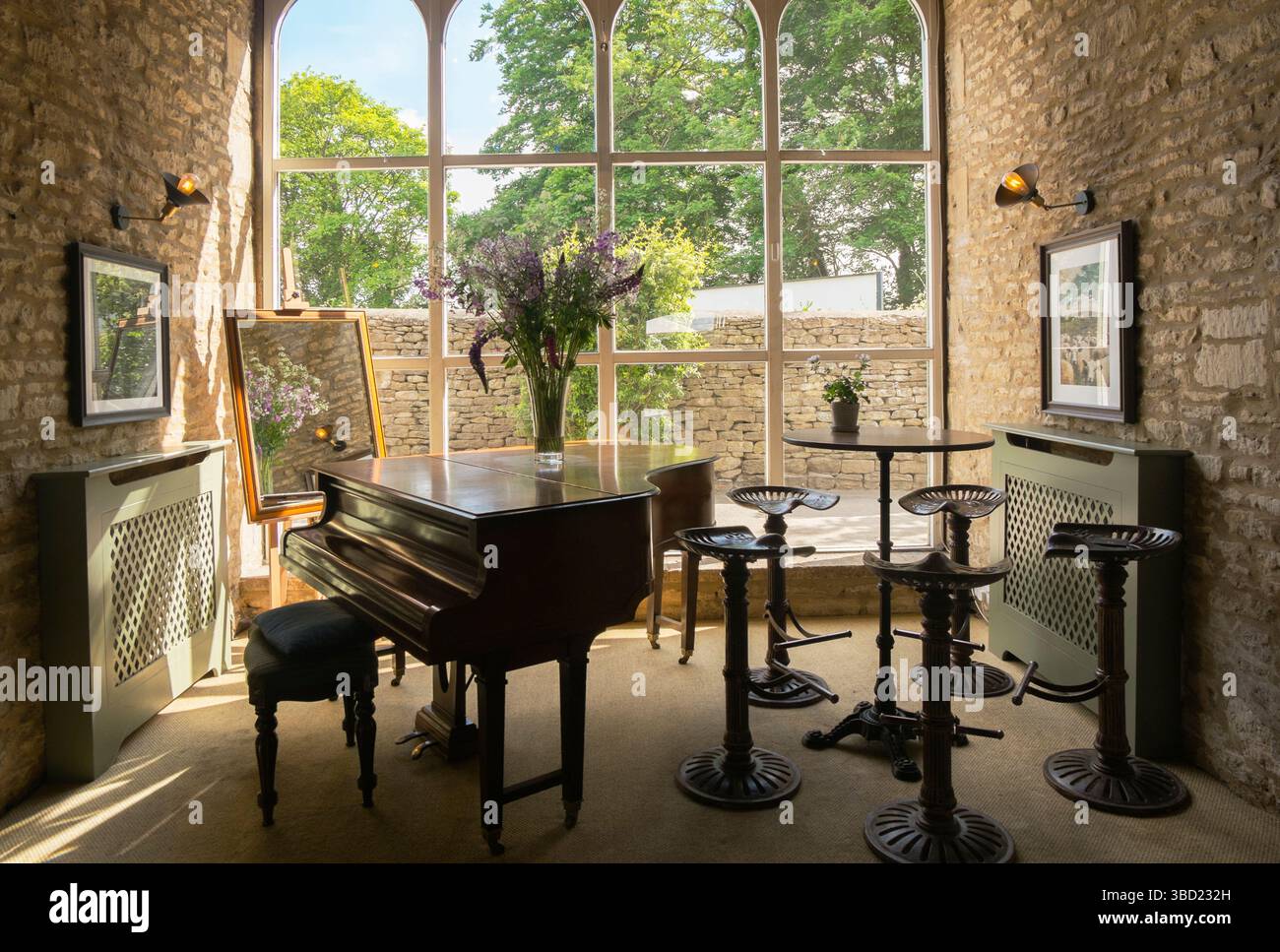 Grand Piano und Vintage-Traktorsitzhocker im Jeremy Clarkson's Pub, The Farmer's Dog, in den Cotswolds, Großbritannien. Stockfoto