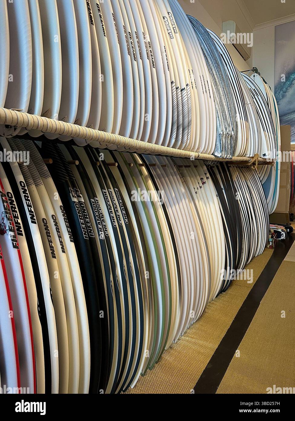 Übersichtlich gestapelte Surfbretter in einem Surfshop, bereit zum Verkauf oder Verleih, mit verschiedenen Designs und Größen für Surfbegeisterte. Stockfoto