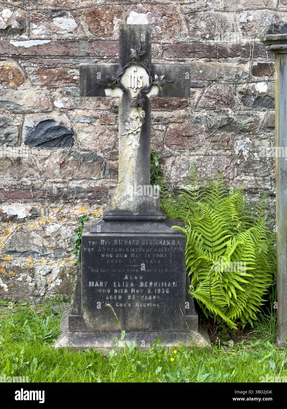 Ein alter Grabstein und ein Steinkreuz auf dem Friedhof in Newport, Pembrokeshire, Wales, Großbritannien Stockfoto